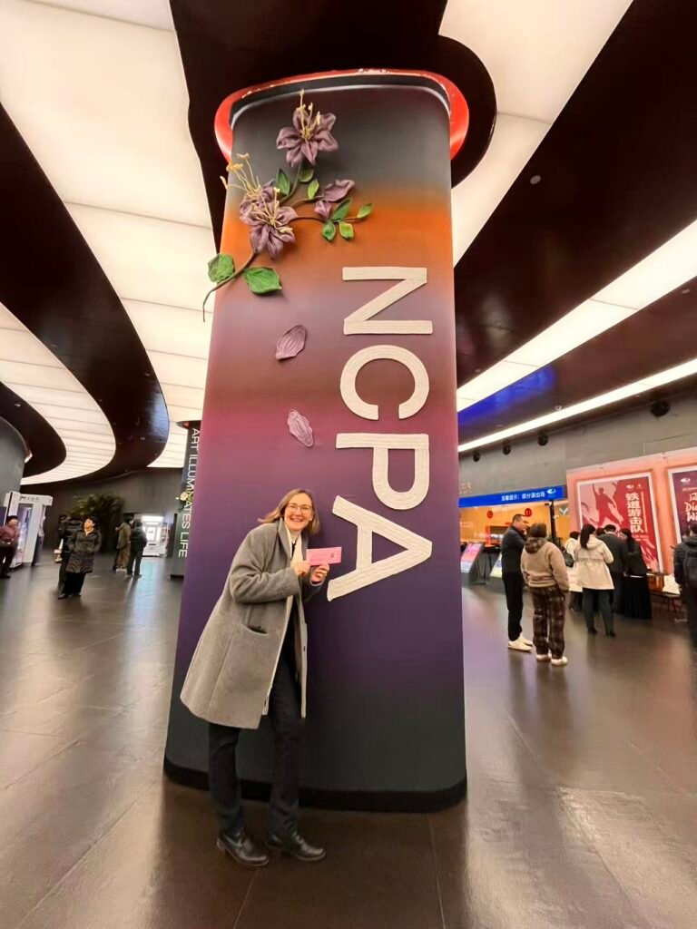 The foreign author of ChinaBlick smiling with a performance ticket next to the NCPA sign inside the National Centre for the Performing Arts in Beijing.