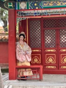 Hanfu in China: When Traditional Dress Moves through Modern Life Young woman wearing traditional pink Ming dynasty Hanfu posing near red pavilion in Beijing.
