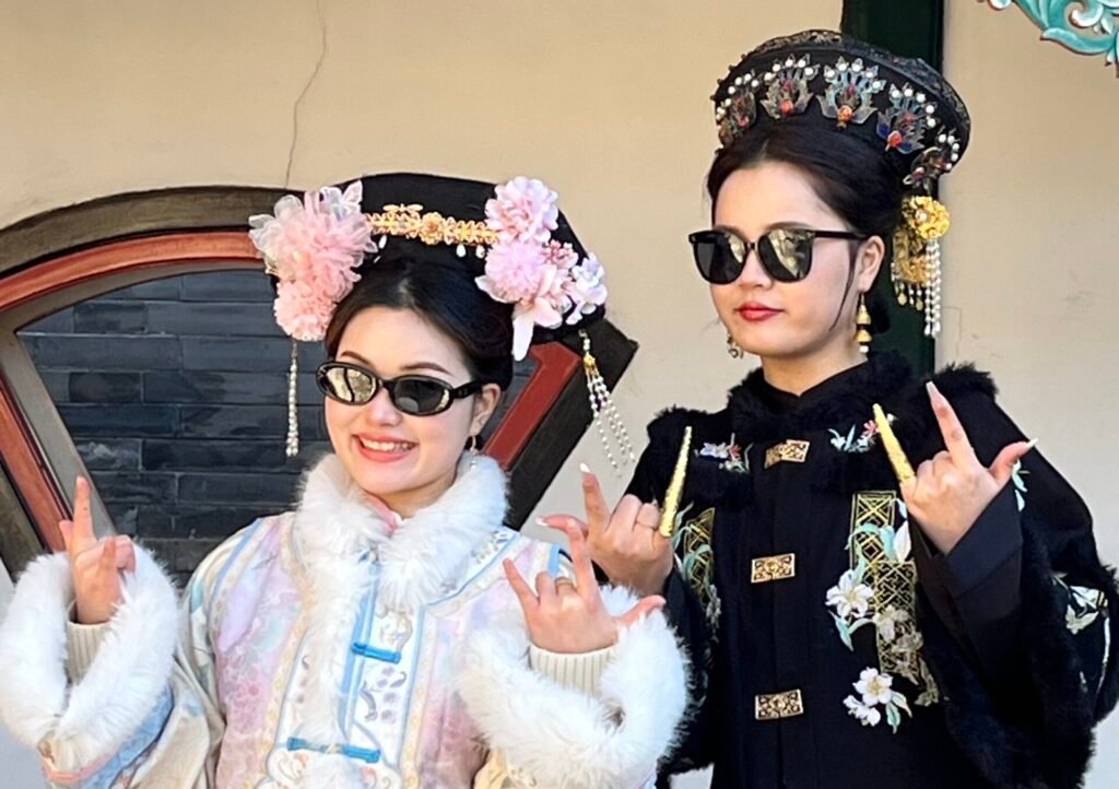 Hanfu in China: When Traditional Dress Moves through Modern Life Two young women wearing traditional Hanfu and modern black sunglasses making rock and roll hand signs.